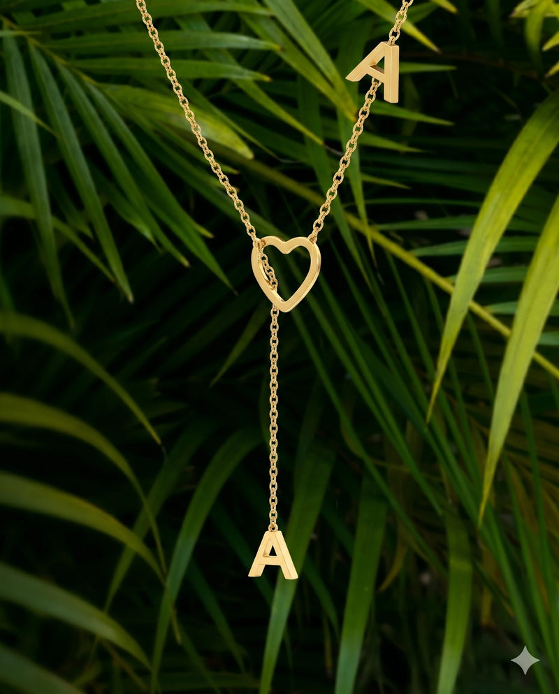 Gold necklace with heart pendant and 'A' letter on a green leaf background